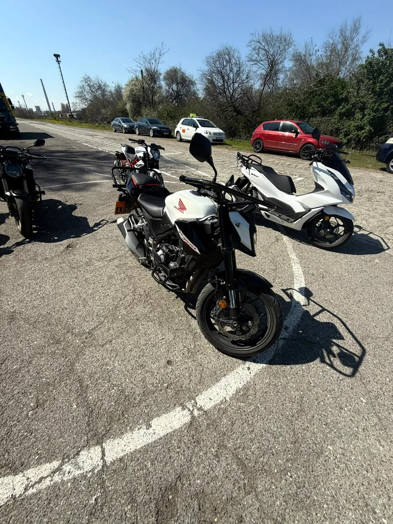 Motocicletă naked neagră și scuter alb, folosite la categoria A