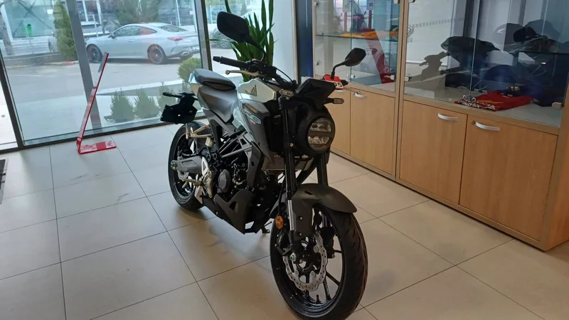 Motocicletă naked verde deschis, văzută din față în showroom