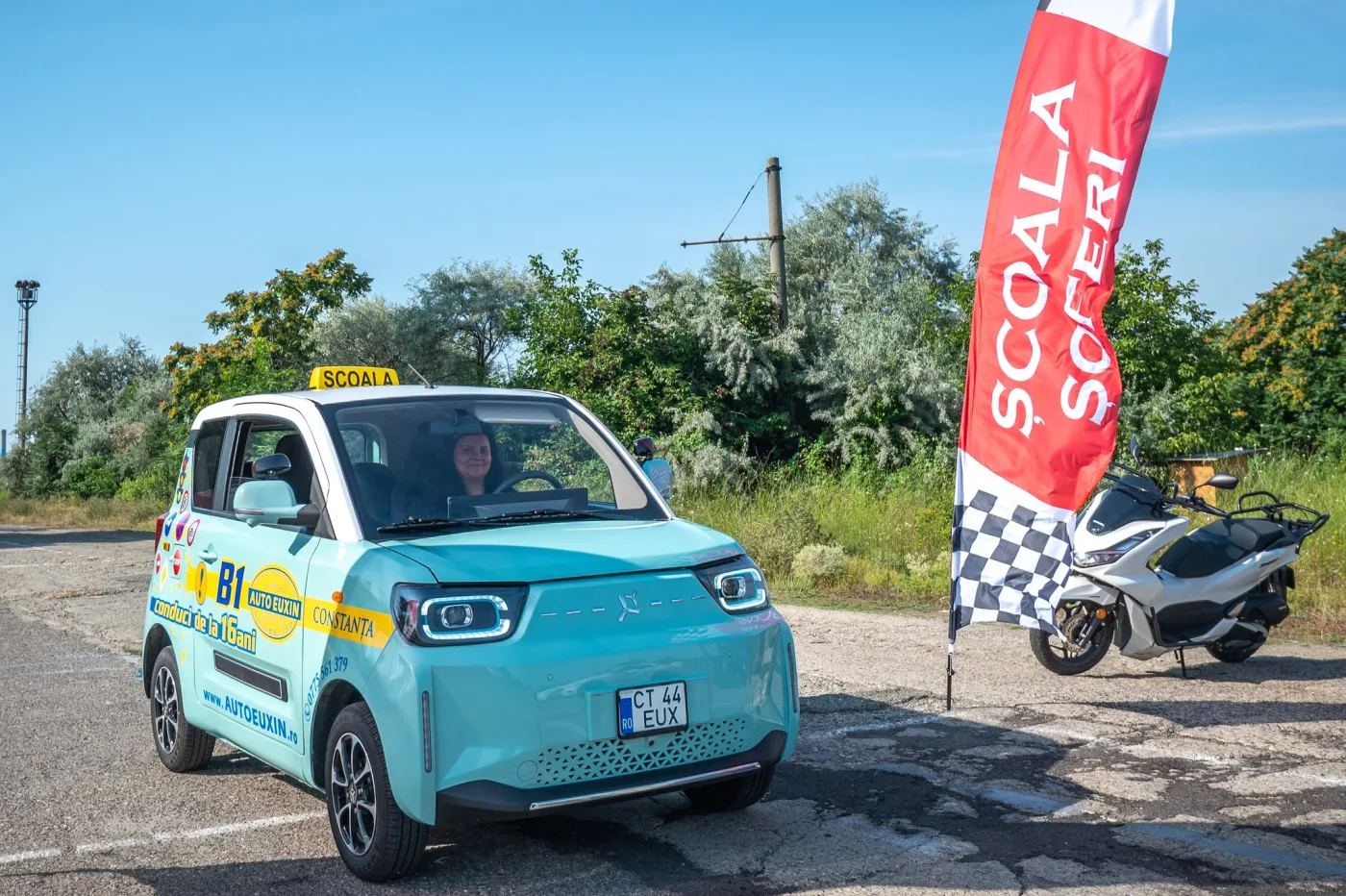 Mașina electrică de categoria B1, turcoaz, cu o cursantă la volan