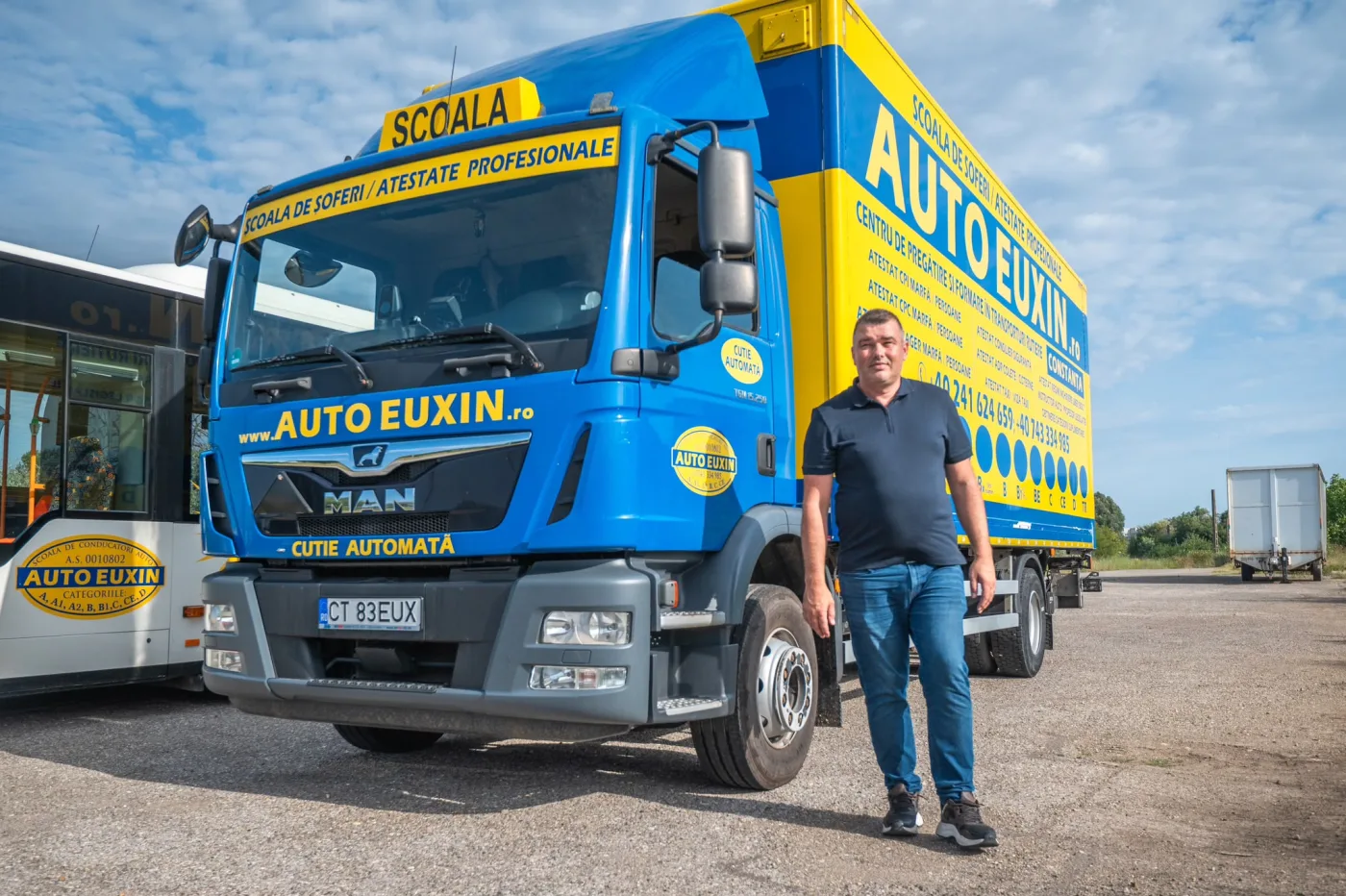 Camion MAN TGM albastru cu galben, cutie automată, și instructorul alături