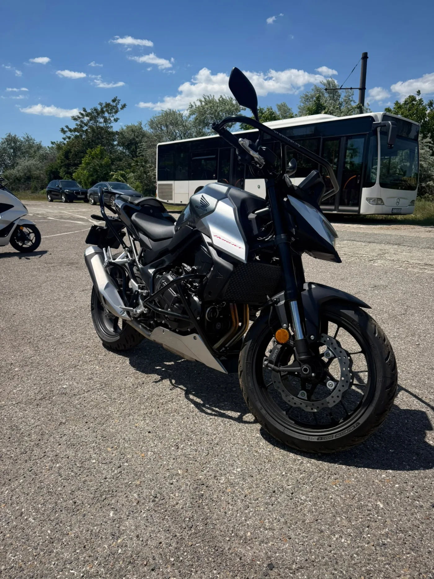 Honda Hornet argintie, în poligon lângă autobuzul de școală